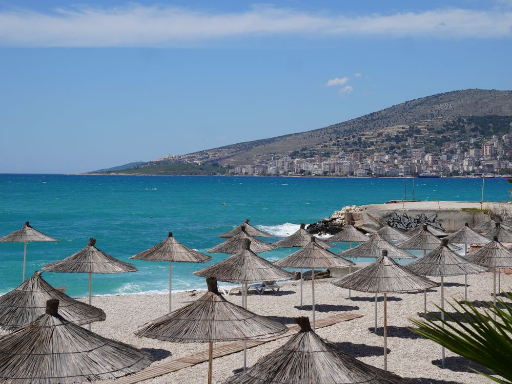 A Mediterranean beach with straw umbrellas and turquoise water