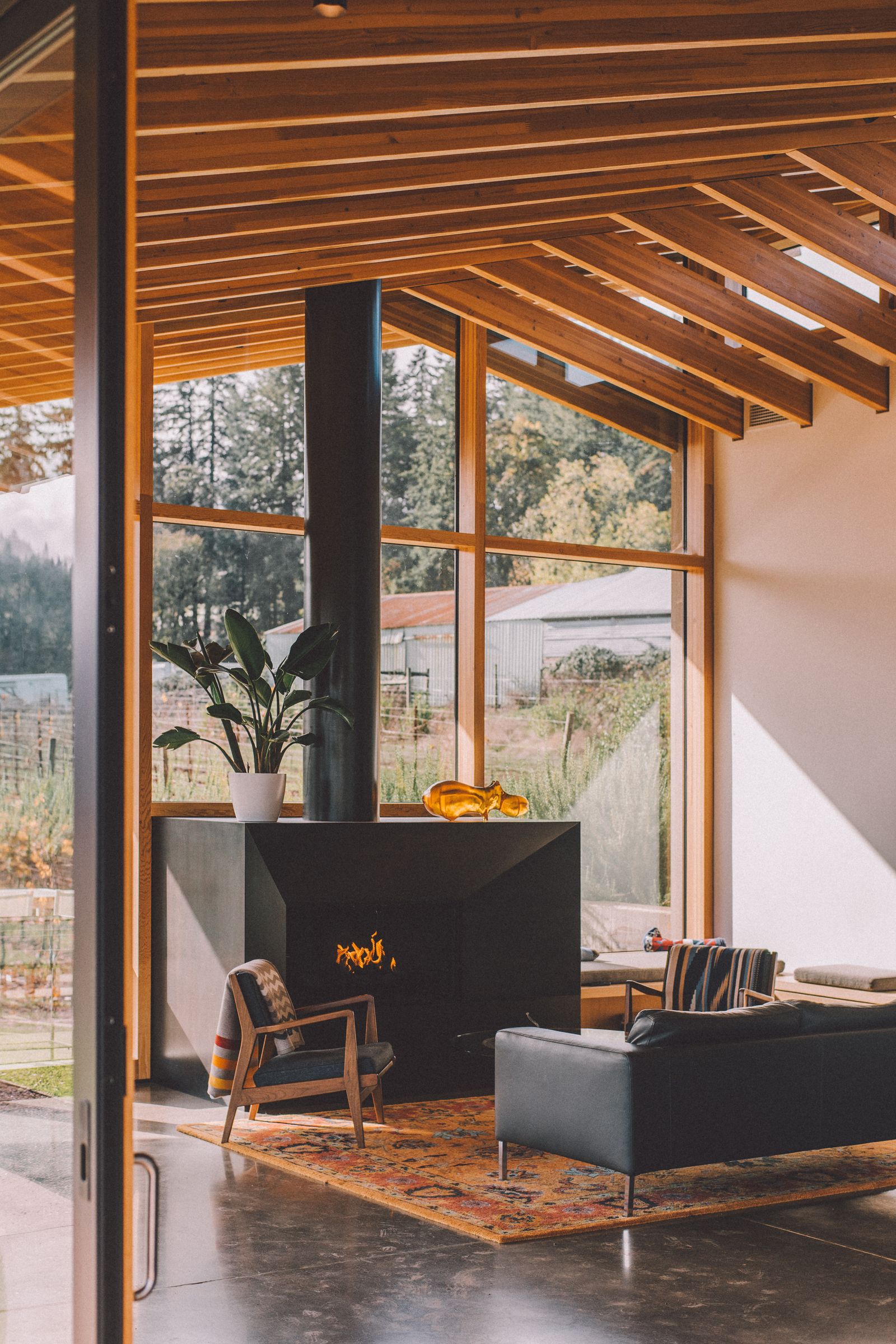 A contemporary living room with large windows and timber beams